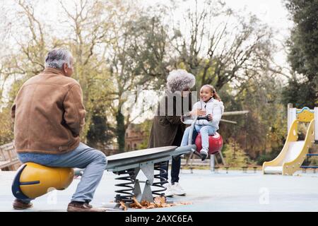 Grands-parents jouant avec la petite-fille sur la mer à l'aire de jeux Banque D'Images