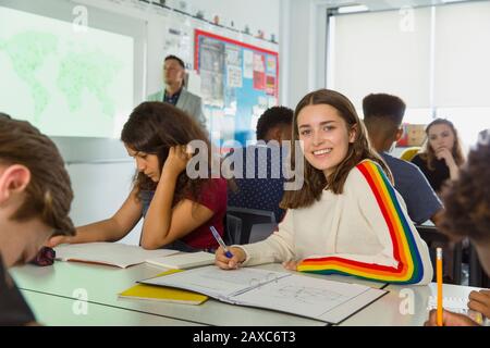 Portrait confiant jeune fille de lycée prenant des notes pendant la leçon de géographie en classe Banque D'Images
