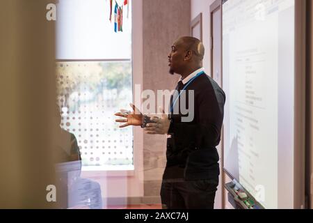 Un instructeur de sexe masculin mène la leçon à l'écran de projection en classe Banque D'Images