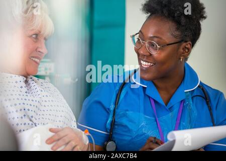 Une infirmière féminine sympathique parle avec un patient senior à l'hôpital Banque D'Images