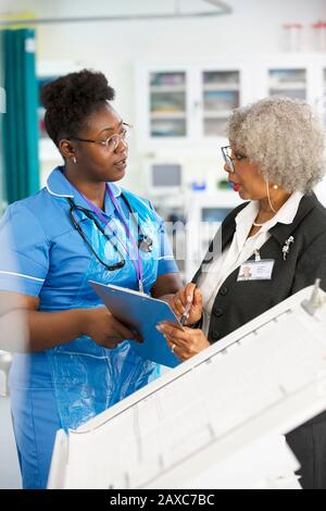 Femme médecin et infirmière avec presse-papiers parler à l'hôpital Banque D'Images