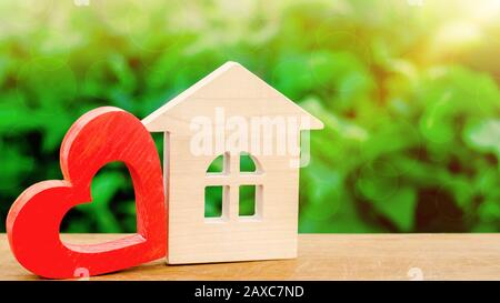 Maison en bois et coeur rouge. Concept de maison douce. Assurance de biens. Une nouvelle maison pour la famille. Louez une maison le jour de la Saint-Valentin. Confort en famille. Afforda Banque D'Images