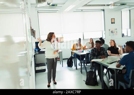 Les élèves du secondaire qui regardent les enseignants en tête de leçon sur le tableau blanc en classe Banque D'Images