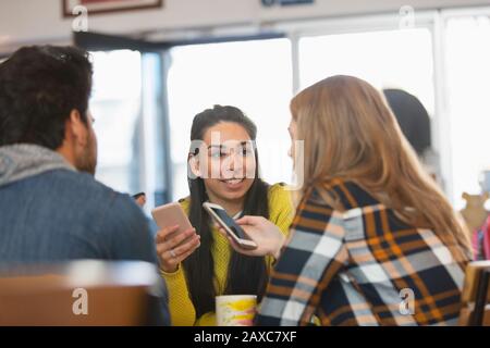 Jeunes amis utilisant des smartphones dans un café Banque D'Images