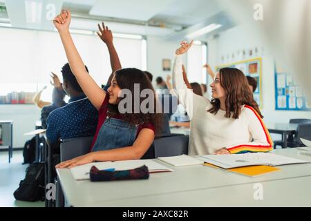 Filles du lycée avec les mains soulevées pendant la leçon en classe Banque D'Images