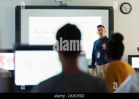 Leçon de leader de l'enseignant secondaire junior masculin à l'écran de projection en classe Banque D'Images