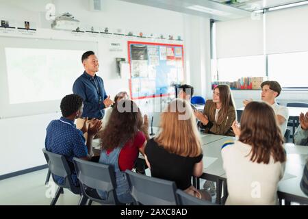 Les élèves du secondaire clapotent pour l'enseignant en classe de débat Banque D'Images