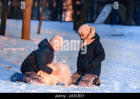 Belles adolescentes s'amuser avec le chien spitz dans le parc en hiver Banque D'Images