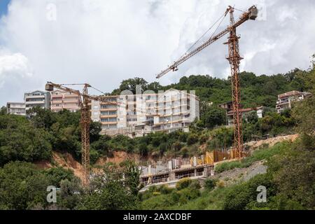 Chantier de construction de bâtiments publics sur des collines près de la côte de la mer. Grues pendant les opérations de levage en montagne Banque D'Images