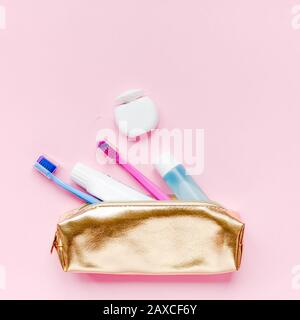 L'hygiène des dents et soins dentaires oral dans les produits cosmétiques sac de voyage golden rose pastel kit fond de couleur avec l'exemplaire de l'espace. Tube de dentifrice vide Banque D'Images