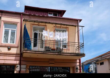 Sur les cordes pendent des t-shirts blancs après le lavage. Balcon au deuxième étage du bâtiment avec clôture en métal. Ouvert en été, balcon avec patte Banque D'Images