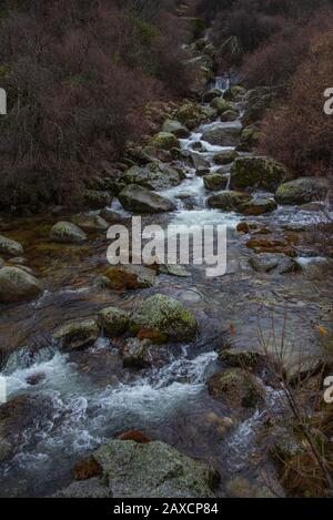 Ruisseau clair avec des roches moussues coule à travers une vallée accidentée à Serra da Estrela, Portugal Banque D'Images