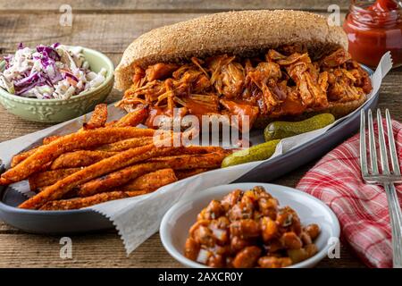 Barbecue végétalien-fruits sur pain de hougie de blé entier. Haricots cuits au four de style sud, frites de patates douces et coleslaw. Banque D'Images