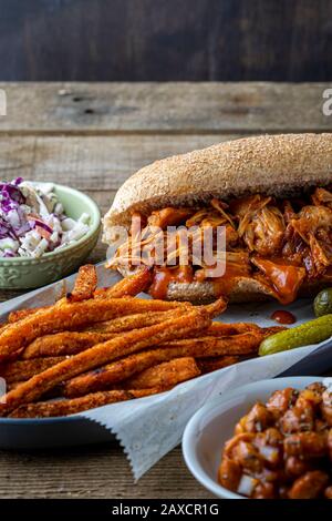 Barbecue végétalien-fruits sur pain de hougie de blé entier. Haricots cuits au four de style sud, frites de patates douces et coleslaw. Banque D'Images