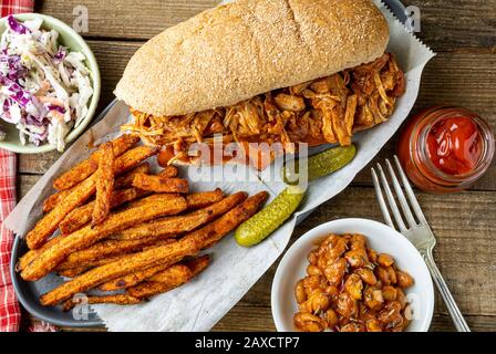 Barbecue végétalien-fruits sur pain de hougie de blé entier. Haricots cuits au four de style sud, frites de patates douces et coleslaw. Banque D'Images