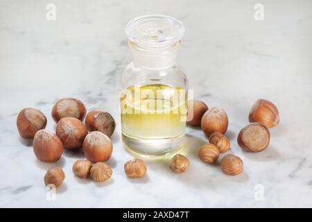 Huile de noisette en bouteille de verre sur table en marbre. Huile pour soins cosmétiques ou de beauté Banque D'Images