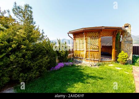 Un belvédère en bois avec un poêle à barbecue en pierre dans l'arrière-cour du cottage. Belvédère à côté de la clôture à l'angle de la cour. Il y a une pelouse verte Banque D'Images