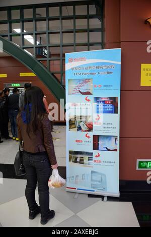 Une femme passager consulte l'affiche d'information à une station de la ligne 1 du métro Harbin, en Chine Banque D'Images