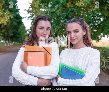 Deux filles écolière amies 11-13 ans, portrait d'été dans la ville dans la rue, dans les mains des carnets de dossiers manuels, se reposant après l'école dans Banque D'Images