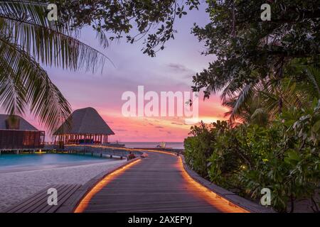 Une promenade menant au bar et au restaurant sur l'eau au coucher du soleil à l'hôtel W aux Maldives Banque D'Images