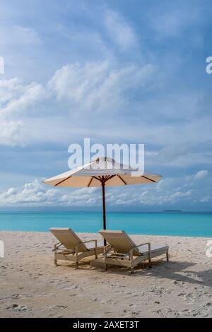 Des chaises longues, un parasol et une superbe mer turquoise sur une île aux Maldives Banque D'Images