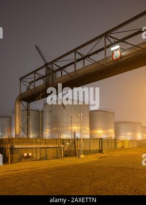 Scène nocturne avec un grand silo et un dépassement de pipeline à l'usine de production pétrochimique, Port d'Anvers. Banque D'Images