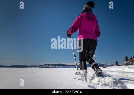 Une femme d'âge moyen raquette dans un après-midi ensoleillé d'hiver. Banque D'Images