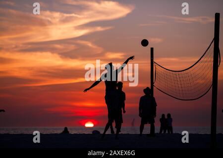 Les gens de Holliday jouent au volley-ball sur la plage au coucher du soleil Banque D'Images