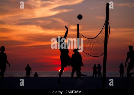 Les gens de Holliday jouent au volley-ball sur la plage au coucher du soleil Banque D'Images