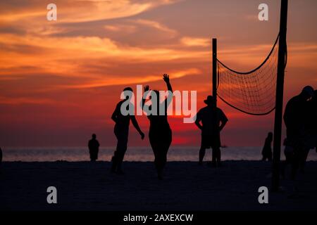 Les gens de Holliday jouent au volley-ball sur la plage au coucher du soleil Banque D'Images