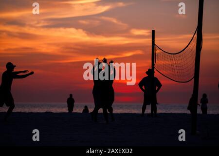 Les gens de Holliday jouent au volley-ball sur la plage au coucher du soleil Banque D'Images