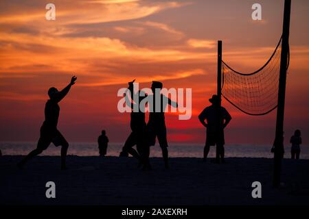 Les gens de Holliday jouent au volley-ball sur la plage au coucher du soleil Banque D'Images