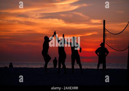 Les gens de Holliday jouent au volley-ball sur la plage au coucher du soleil Banque D'Images