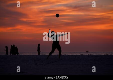 Les gens de Holliday jouent au volley-ball sur la plage au coucher du soleil Banque D'Images