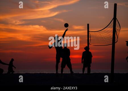 Les gens de Holliday jouent au volley-ball sur la plage au coucher du soleil Banque D'Images