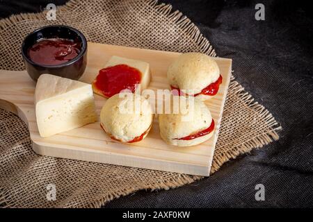 Pain au fromage maison brésilien AKA 'pao de queijo', farci avec dessert de goyave, sur un fond rustique. Banque D'Images