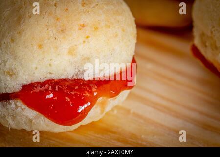 Pain au fromage maison brésilien AKA 'pao de queijo', farci avec dessert de goyave, sur un fond rustique. Banque D'Images