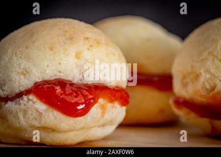 Pain au fromage maison brésilien AKA 'pao de queijo', farci avec dessert de goyave, sur un fond rustique. Banque D'Images