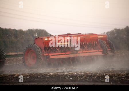 Semoirs mécaniques agricoles de cultures céréalières. Le tacteur à semoir saute le grain dans le champ. Un agriculteur d'un tracteur avec semoir traite le champ. Banque D'Images