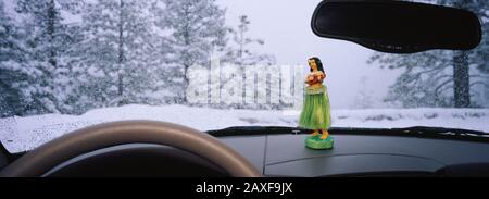 Gros plan de la figurine d'une jeune fille hula sur le tableau de bord d'une voiture dans une forêt, Yosemite National Park, Californie, États-Unis Banque D'Images