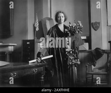 1921, Pennsylvanie , États-Unis :LE célèbre physicien IRENE JOLIOT CURIE ( 1897 - 1956 ) est présenté en régalia académique le 23 mai 1921, lorsqu'elle a accepté un diplôme honorifique à l'Université de Pennsylvanie au nom de sa mère Marie Sklodowska Curie ( 1867 - 1934 ). Accompagné de ses filles Ire'ne et Eve, Marie Curie a eu un calendrier épuisant d'apparitions lors de sa tournée américaine de 1921, acceptant des prix et un don de radium pour ses recherches, organisé par diverses associations de femmes et groupes scientifiques. . Photo De James Stokley . Irene a reçu conjointement le prix Nobel de chimie Banque D'Images