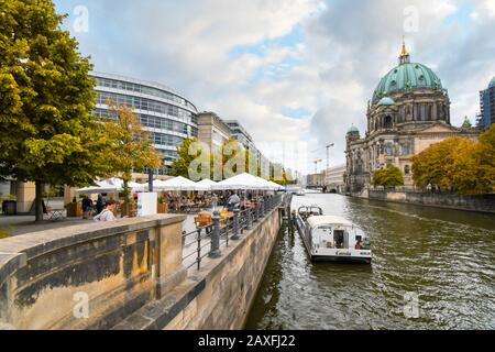 Les touristes apprécient un après-midi d'automne dans un café au bord de la rivière Spree avec vue sur la cathédrale de Berlin. Banque D'Images