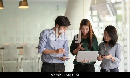 Portrait de jeunes concepteurs passionnés d'interface utilisateur travaillant et discutant du projet tout en se tenant dans la salle de bureau Banque D'Images