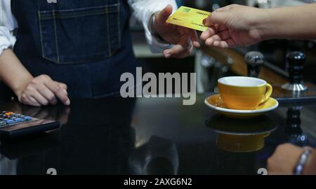 Le barista qui sert le client et la femme paie le café par carte de crédit dans le café Banque D'Images