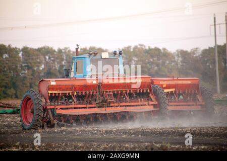 Semoirs mécaniques agricoles de cultures céréalières. Le tacteur à semoir saute le grain dans le champ. Un agriculteur d'un tracteur avec semoir traite le champ. Banque D'Images