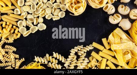 Les pâtes italiennes avec copie espace, d''une télévision jeter d'une variété de types de pâtes, tourné à partir de ci-dessus, sur un fond noir avec une place pour le texte Banque D'Images