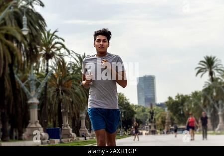 Jeune homme latin qui fait du jogging ou de la course dans un parc de la ville Banque D'Images