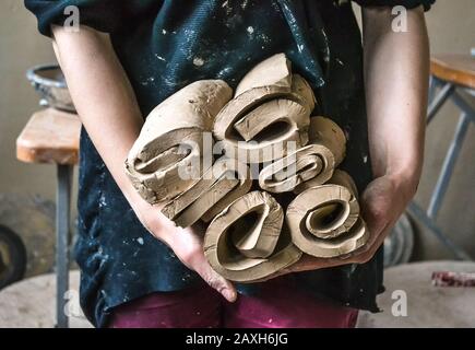 Maître potter girl holding a beaucoup coupé et couches torsadée rouleau de pièces d'argile. Creative studio potter. L'assistant au travail de la poterie cruche Banque D'Images