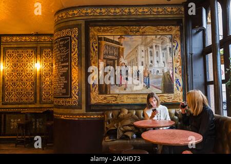 Angleterre, Londres, Shoreditch, Spitafields, The Ten Bells Pub, Deux Femmes Clientes Regardant Iphones Banque D'Images