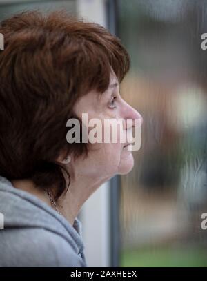 Lady regardant la forte pluie de sa fenêtre de maison Banque D'Images